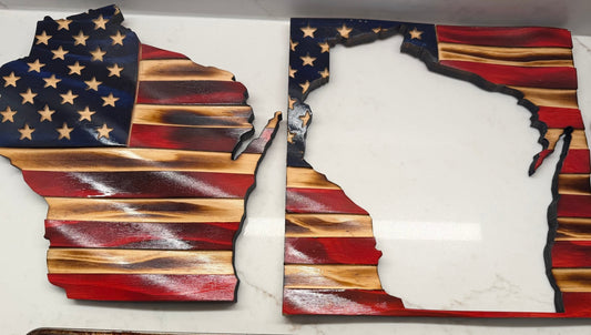Wooden crafts shaped like the state of Wisconsin with American flag design on a white surface.